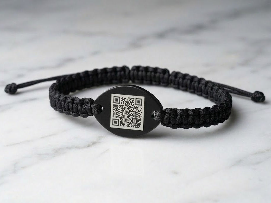 Black braided bracelet with a black tag featuring a QR code on a black surface